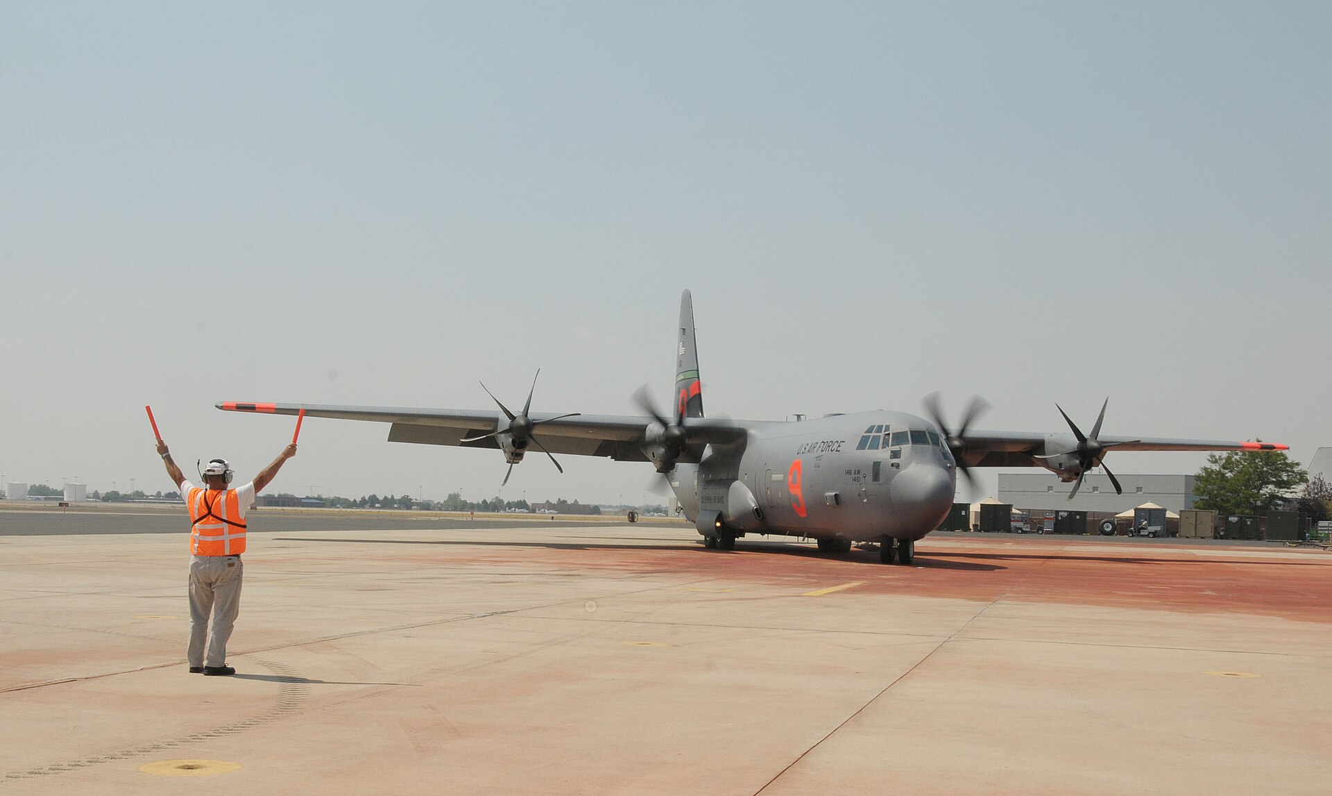 An air tanker dropping retardant over forested terrain.
